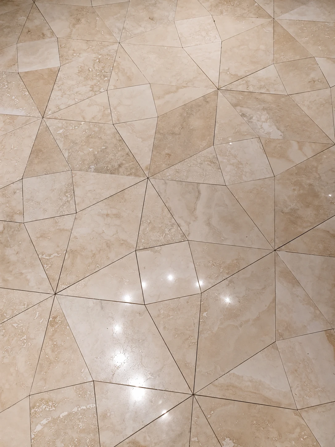 Pale natural stone floor tiles laid in an irregular geometric pattern
